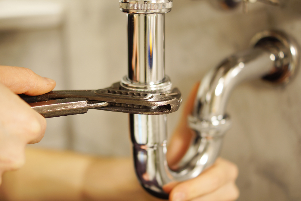 under-sink plumbing and wrench held by plumber